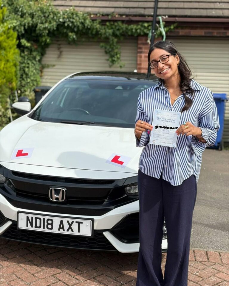 Neha Thomas celebrating her first-time manual driving test pass in Doncaster with instructor Ionut